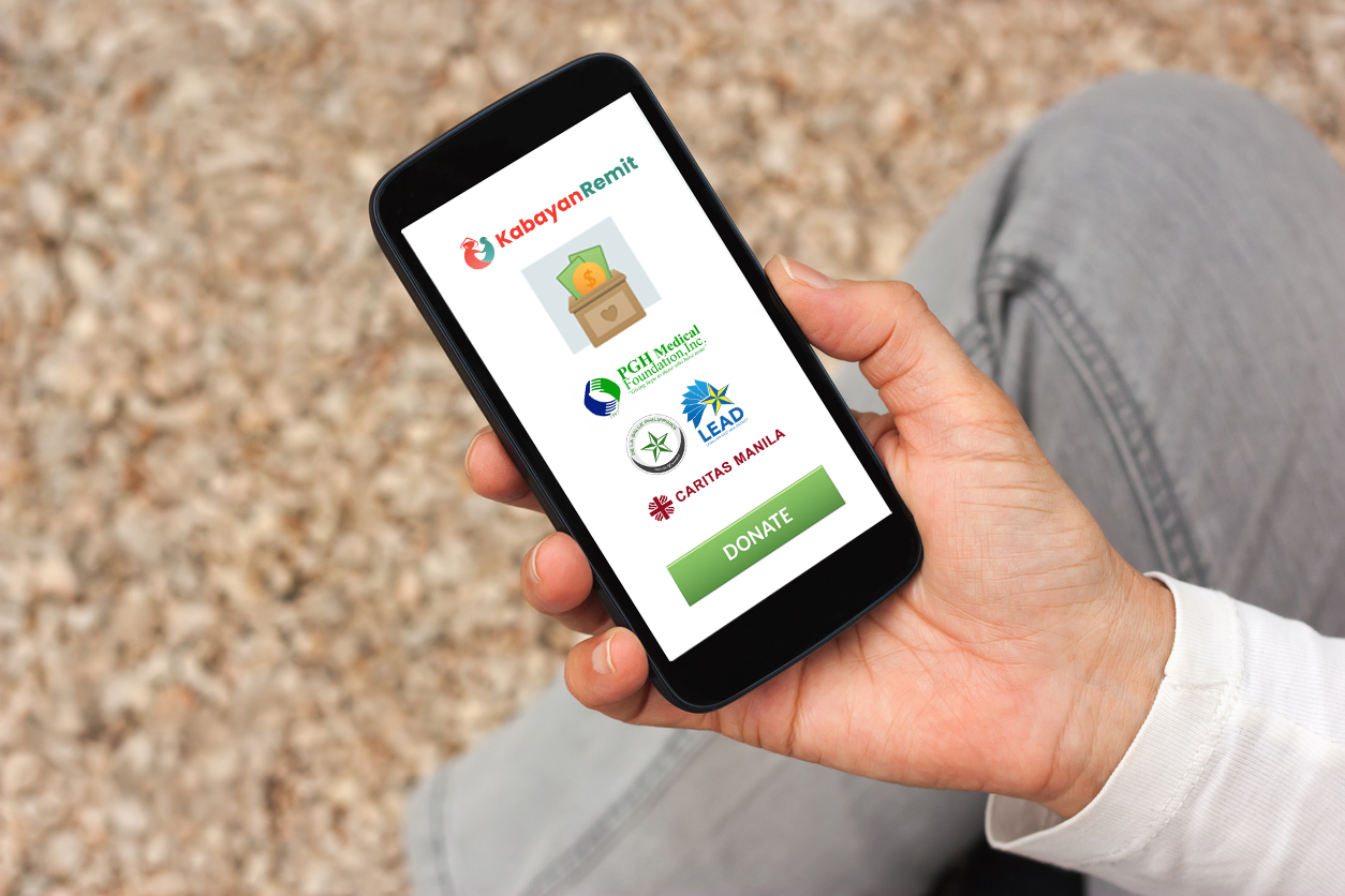 A hand holding a phone that shows Kabayan Remit's partner charities for donation