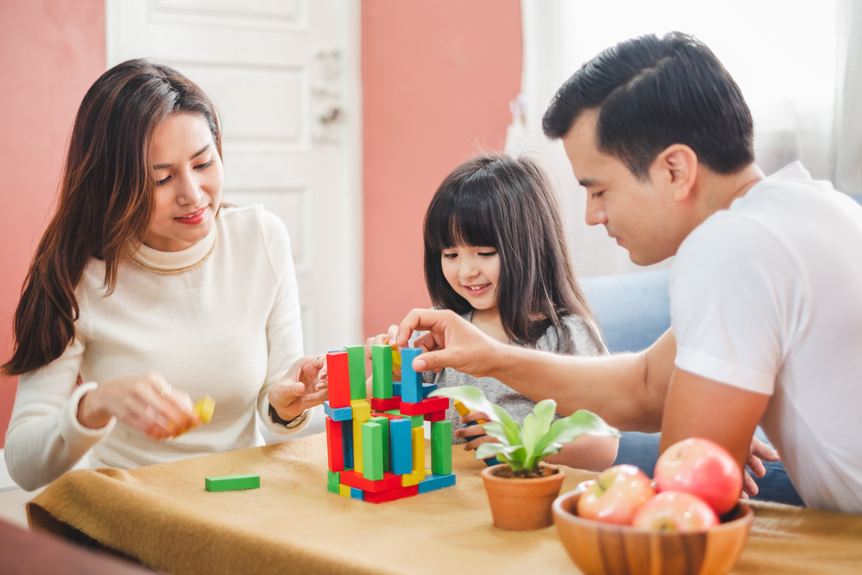 Mum, dad and daughter playing jenga together.